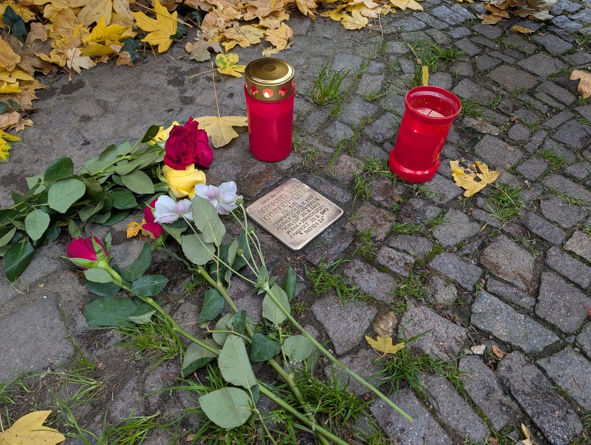 Gedenkstein mit Blumen und Kerzen