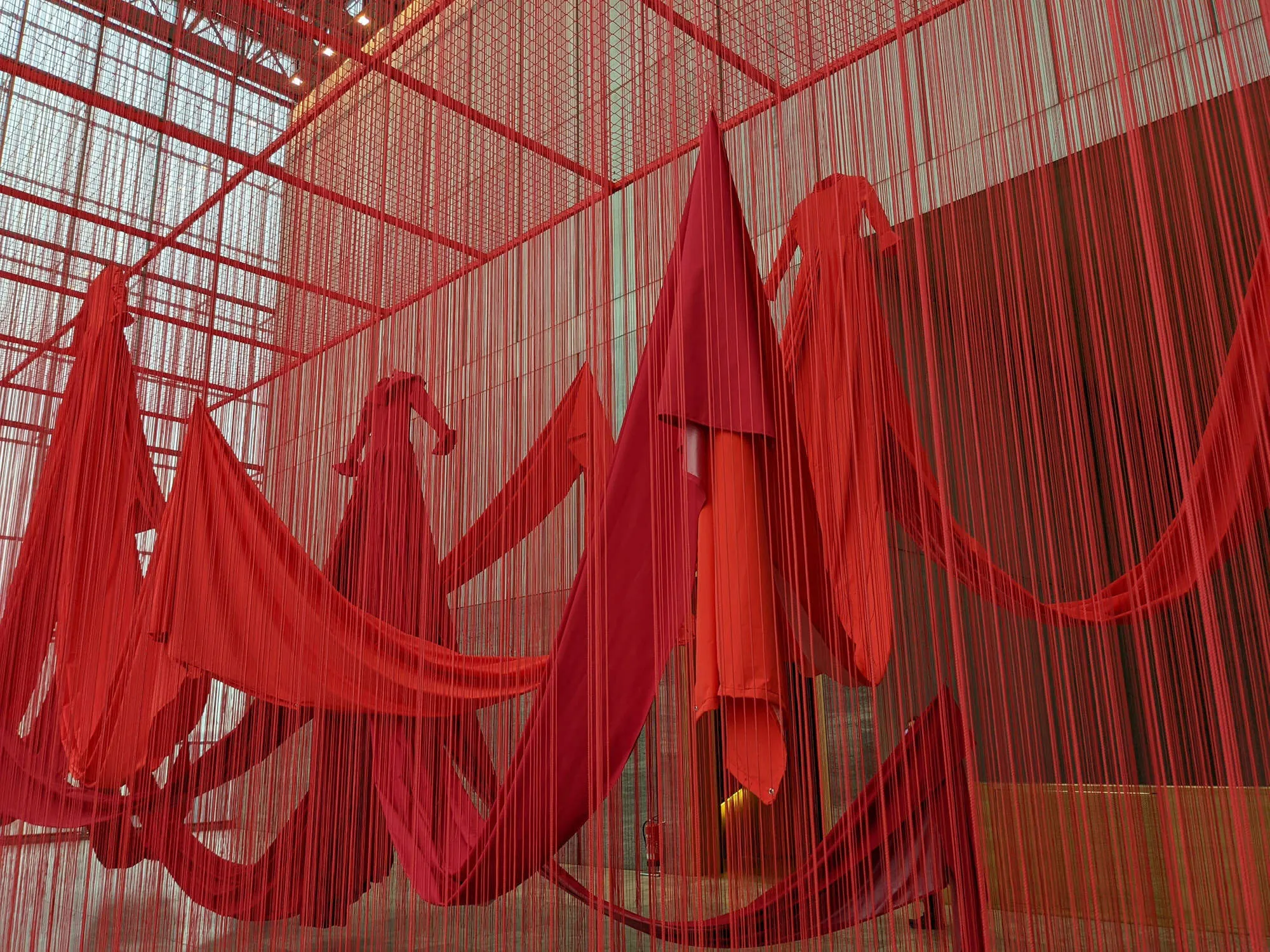 Großräumiges Kunstwerk mit roten Kleidern und Fäden